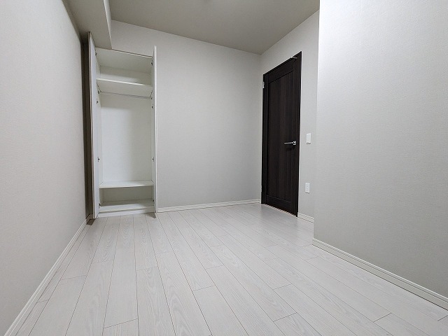 洋室です。床は白いフローリングで壁はライトグレーのクロスです。収納付きです。ドアは白に映えるダークブラウンです。
