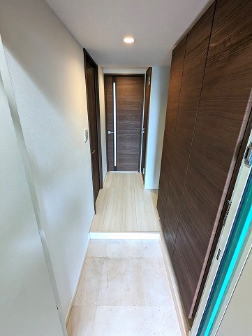 玄関から廊下です。床と壁が白く、建具の色は茶色の木目調で引き締まった印象です。