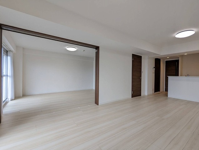 床は白のフローリングで木目も薄く見えます。リビングと隣の洋室はひとつながりになっています。